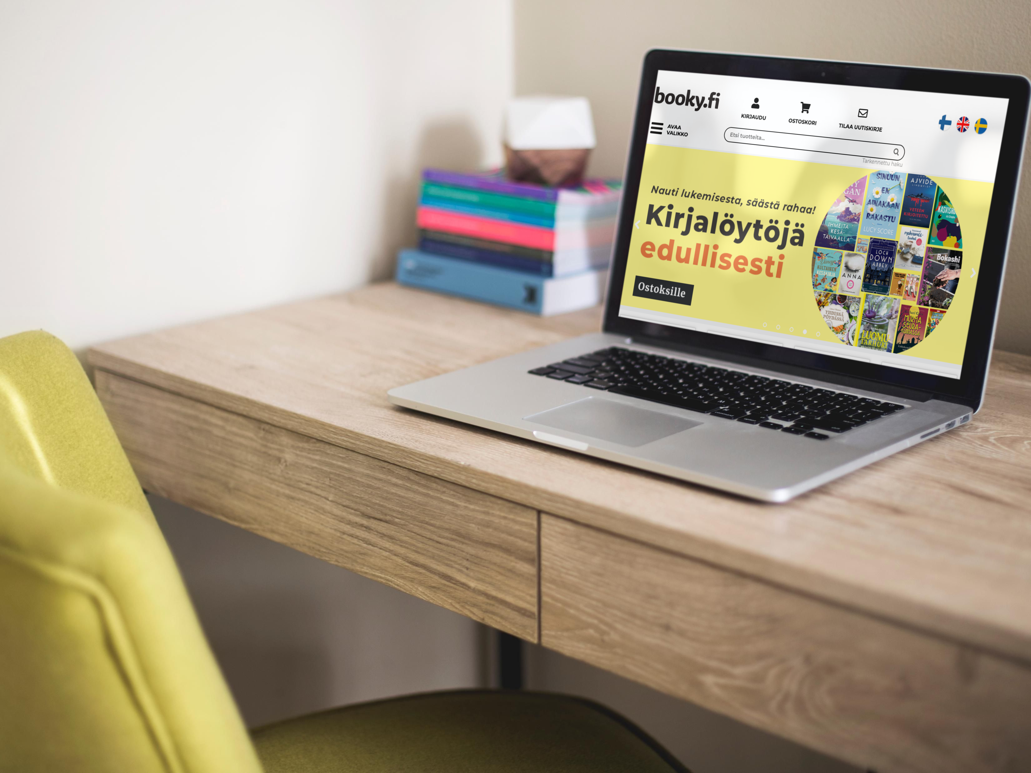 Kirjoituspöydällä on tietokone, jossa näkyy booky.fi sivuston aloitussivu